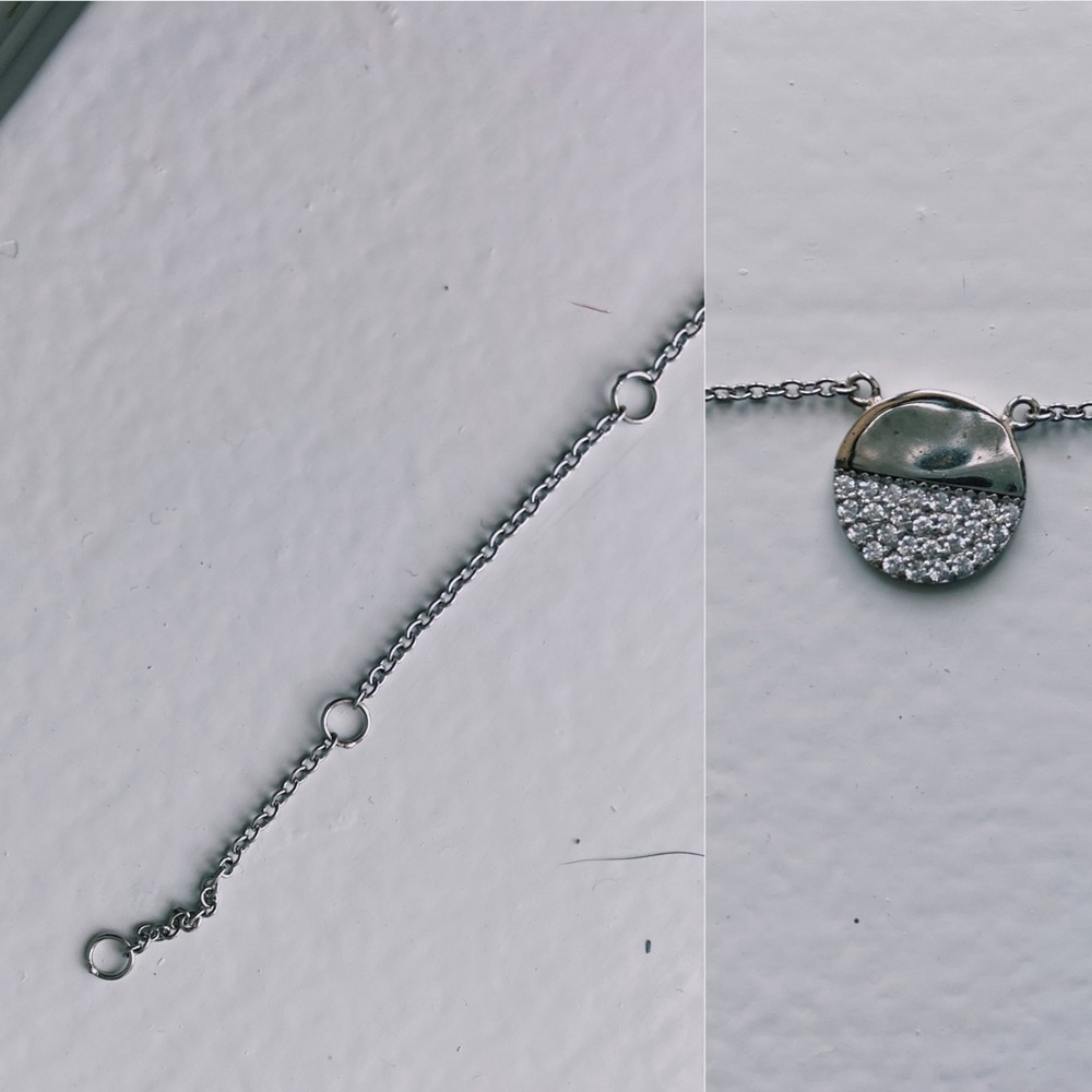 silver necklace. circle with stones on it.